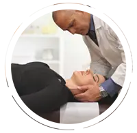 Chiropractor performing a neck adjustment on a female patient lying on a treatment table.