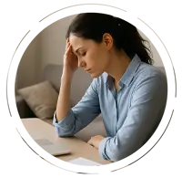 Young woman with poor posture sitting at a desk, resting her forehead on her hand in fatigue while working on a laptop, showing signs of exhaustion and slouching.