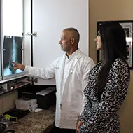 New Patients -Doctor pointing at a spinal X-ray while explaining the results to a standing patient.